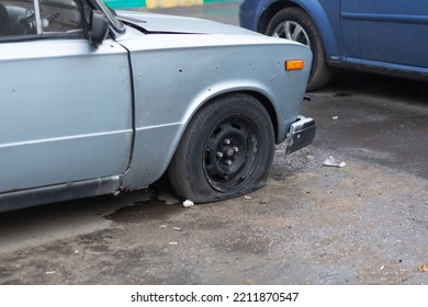 An Old Rusty Car With A Punctured Front Wheel.