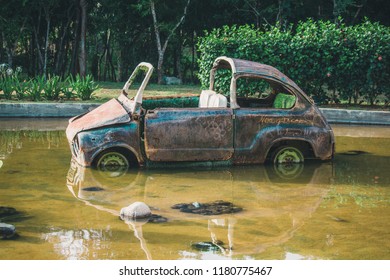 An Old Rusty Car Stuck In A Pond