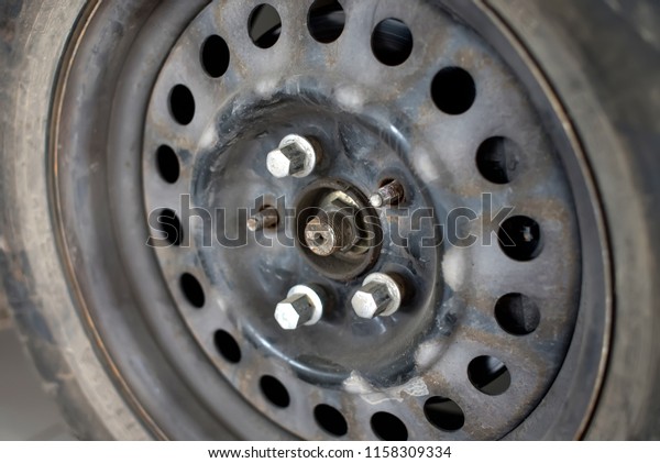 old rusty car wheel disk with\
unscrewed bolts. replacement of a car tire. tire\
fitting