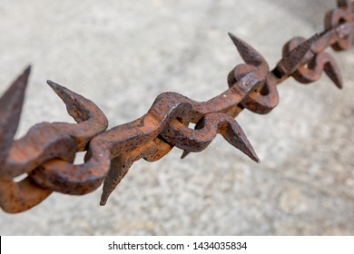 Old rusty chain with iron spikes. Abstract chains from the middle ages isolated on gray outdoor blurred background. Old vintage weathered iron chain links closeup. Old chain with thorns.