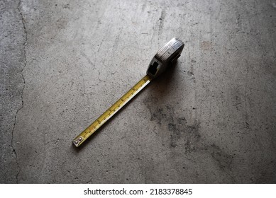 Old Rusty Chrome Metal Yellow Measuring Tape On Concrete Garage Floor. 