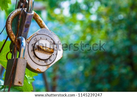 Old and rusty combination locks attached to locks.