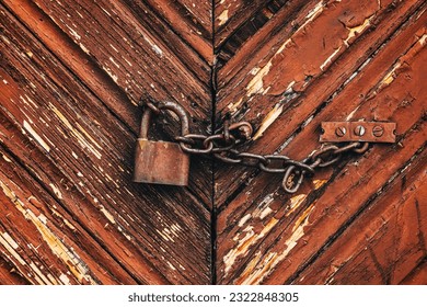 Old rusty corroded padlock with chain on wooden farm barn door as background