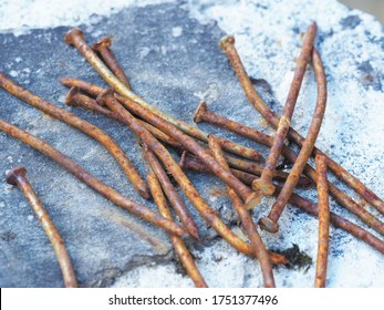 old rusty curved nails lie in a pile on a concrete post