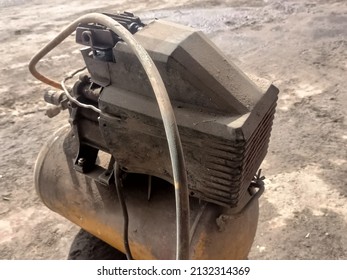 Old, Rusty And Damaged Air Compressor On Industrial Workshop. Old And Rusty Piston Air Compressor Used In The Factory, Air Compressor Used For Air Filling In Rubber Tube. Industrial Equipment.