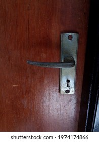 An Old Rusty And Dirty Doorknob With A Worn-looking Wooden Door