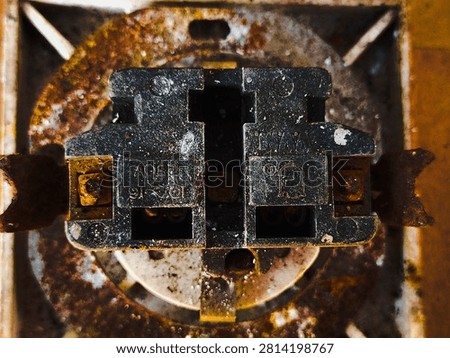 Old rusty electrical socket mechanism close up. Vintage dirty power outlet internal parts with heavy corrosion.
Macro photograph of the inside components of an antique wall power outlet. The black plastic body and surrounding metal ring show severe rust stains, oxidation, and grime buildup. Perfect for industrial grunge themes, hazardous electrical wiring concepts, vintage hardware, or texture backgrounds. Taken In Dau, Malang, East Java Indonesia, On July 19 2026