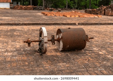 Old rusty farm soil compactor abandoned on a brick floor, showing obsolete rural machinery and the transition from manual labor to modern agriculture