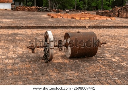 Old rusty farm soil compactor abandoned on a brick floor, showing obsolete rural machinery and the transition from manual labor to modern agriculture