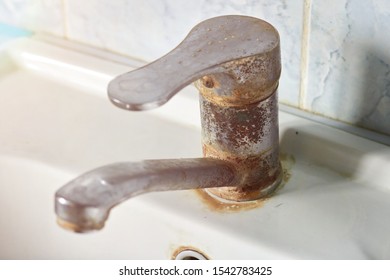 Old, rusty faucet in the kitchen, limestone, scum, need a replacement.