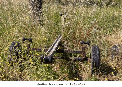 Old rusty and forgotten boat trailer being slowly reclaimed by nature, standing in a field of tall grass - Powered by Shutterstock