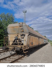Old rusty freight rail wagon standing on railway tracks in a railway yard under a dramatic cloudy sky. Industrial transportation, railway infrastructure, freight logistics and abandoned rolling stock concept with copy space.