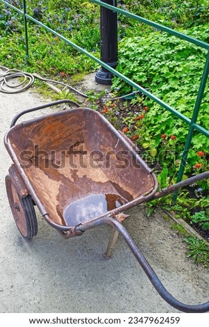 An old rusty garden wheelbarrow after a rain on a summer day