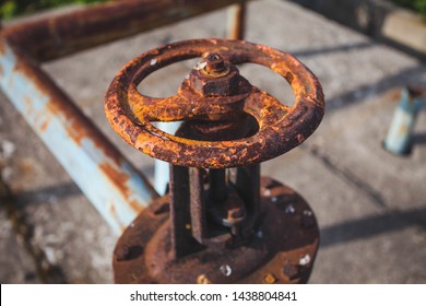 An old rusty gas control valve on the wall. Industrial valve in a large system. Rusty pipes. Old water valve.