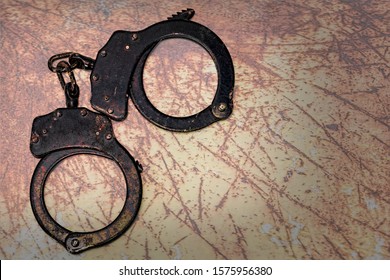 Old And Rusty Handcuffs On Table