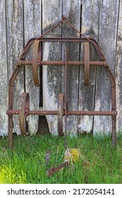 Old Rusty Harrow By A Wooden Wall