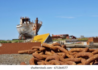 Old rusty heavy chain in front of a shipwreck in the Icelandic dry dock in the Akranes town as a symbol of corrosion and decay 