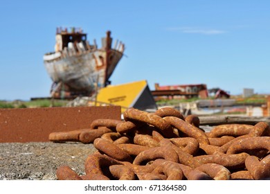 Old rusty heavy chain in front of a shipwreck in the Icelandic dry dock in the Akranes town as a symbol of corrosion and decay 