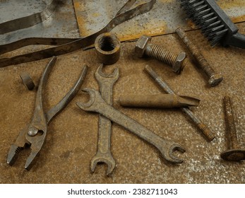  Old rusty instruments open end wrench, pliers, rasp and others lie on the rusty sheets metal
