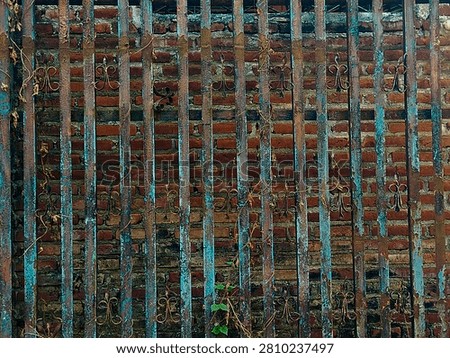 Old rusty iron gate texture background with peeling blue paint. Vintage weathered metal fence against a red brick wall. Taken In Dau, Malang, East Java Indonesia, On July 12 2026