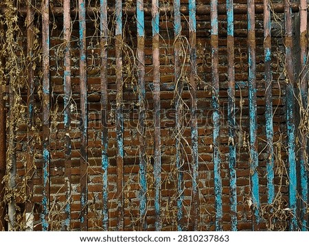 Old rusty iron gate texture background with peeling blue paint. Vintage weathered metal fence against a red brick wall. Taken In Dau, Malang, East Java Indonesia, On July 12 2026