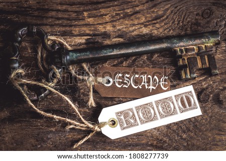 an old rusty key on a ribbed wooden table and  labels with the text Escape room