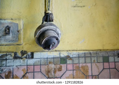 Old and rusty light switch on yellow wall