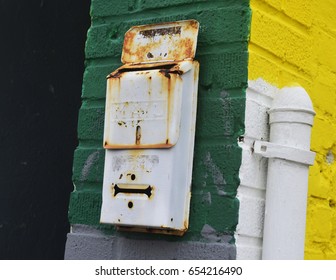 Old Rusty Mailbox On Green And Yellow Brick Building In Urban Neighborhood 