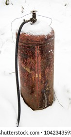 Old Rusty Metal Gas Cylinder With A Hose Covered With Snow