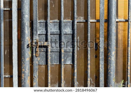 Old rusty metal gate with vertical bars and heavy lock chain