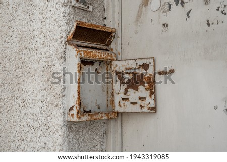 Old rusty metal mailbox with open door on white wall (538)