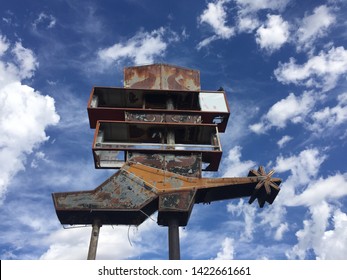 Old Rusty Metal Western Wear Cowboy Boot Store Sign With A Cloud Filled Blue Sky In The Background. 