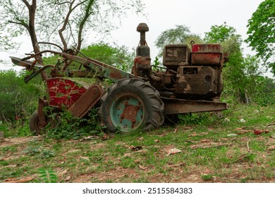 old, rusty motor cultivator overgrown with vegetation, abandoned in forested area with trees and shrubs in background - Powered by Shutterstock