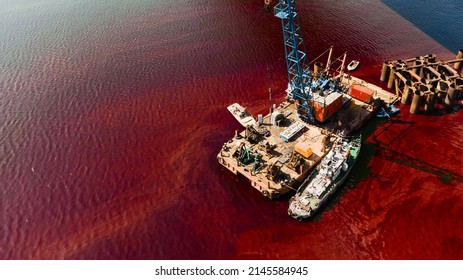 An Old Rusty Red And Brown Barge In Red Water. Urban And Industrial Decay Concept.