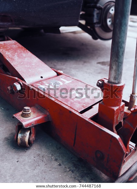 Old and Rusty\
Red Car jack to lift car for change the wheel on the repair stand\
at garage. with copy space.