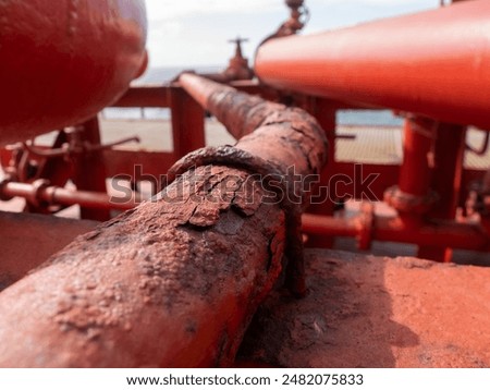 Old and rusty red cargo pipe on a ship