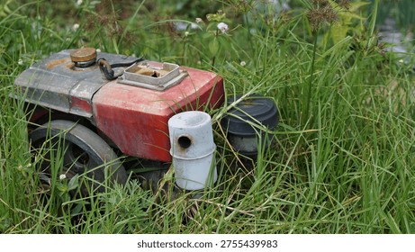Old rusty red diesel engine water pump located in green grass field. Agriculture concept