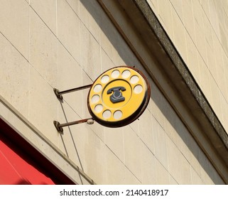 Old  rusty round  public telephone sign  with dial phone,  still hanging on a stone wall.  Vintage public italian signpost. - Powered by Shutterstock