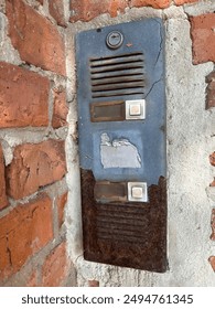 Old rusty ruined intercom on a brick wall