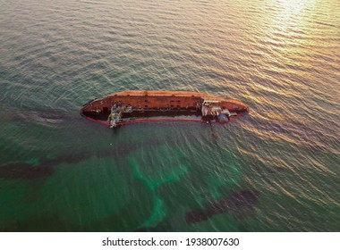 The old rusty ship was stranded by a storm. Oil spill from a tanker, environmental pollution. Ship at sunrise - Shutterstock ID 1938007630