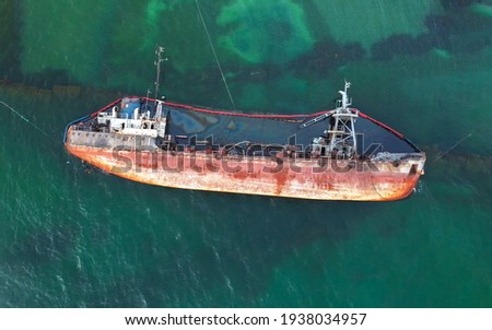 The old rusty ship was stranded by a storm. Oil spill from a tanker, environmental pollution. Top view of a rusty ship in the sea.