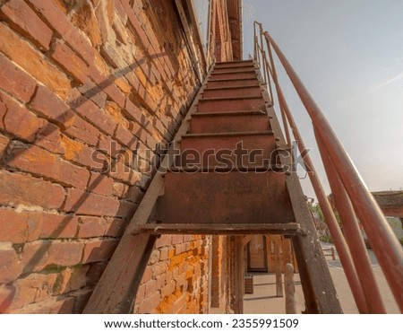 Old rusty steel stairs by the brick wall of a historic mill. Historic red brick mill and stairs 