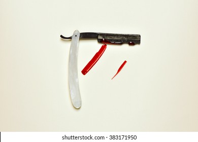 An Old And Rusty Straight Razor Full Of Blood On An Off-white Background