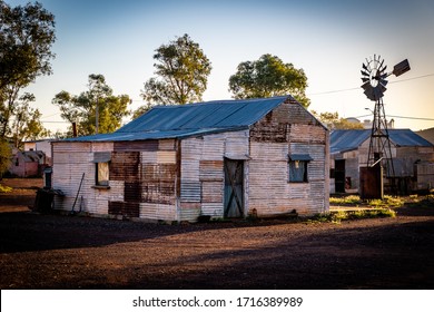 Old rusty tin shack in the Australian Outback with a windmill in the background.