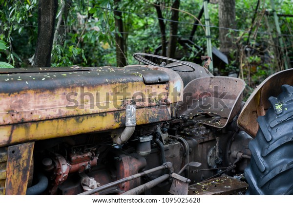 Old rusty tractor shot near the village in\
Bangkok, Old abandoned tractor with trees behind, Image of old\
tractor shot on the sunny day in\
Bangkok