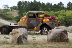 An Old Rusty Truck Is Decorated With Pumpkins And Gourds On The Side Of A Country Road In Early Autumn