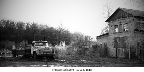 An Old Rusty Truck Stands On A Derelict Site.