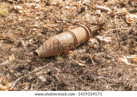 Old rusty unexploded ordnance of wartime times in the forest