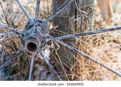 Old Rusty Wagon Wheel Leaning On A Wooden Fence Post