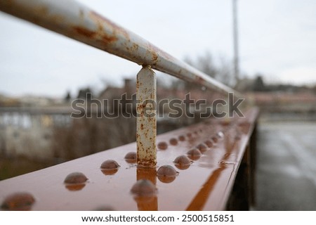 Old rusty wet railing of a small bridge, rainy day in winter